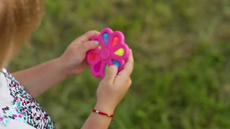 primer plano de una niña jugando a girar con pop it juguete sensorial contra el estrés en el parque, alivio de la ansiedad por estrés