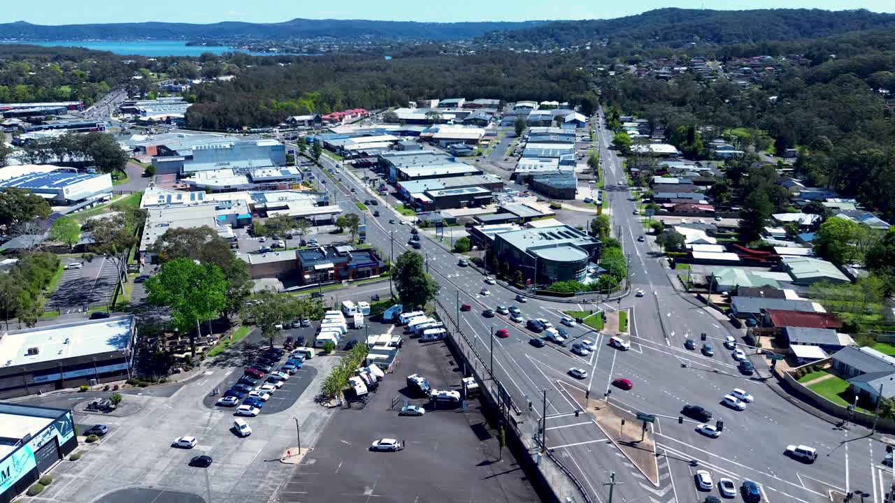 Drone aerial landscape of car vehicle traffic driving along main road town suburbs of Erina with shopping district and urban plaza on Central Coast Australia tourism travel transport infrastructure