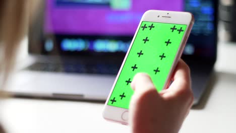 female hand scrolls the tape on a smartphone. green screen with trackers