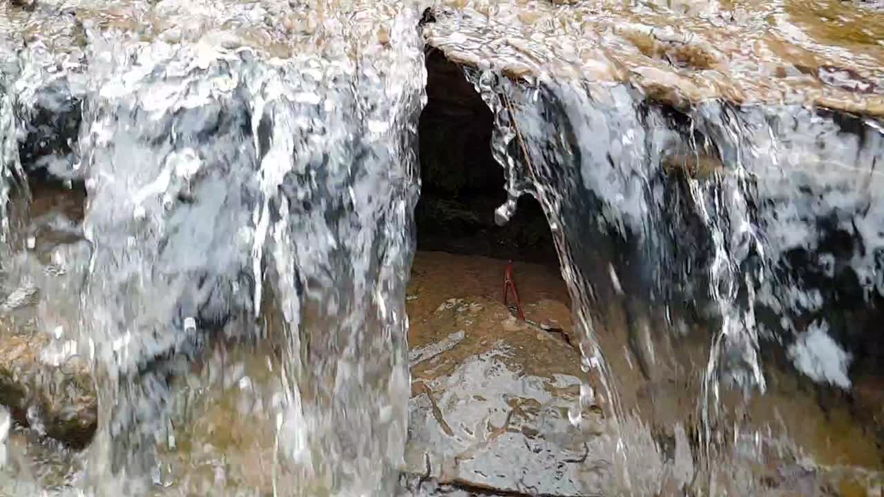 cachoeira fluindo de um córrego de água de nascente de montanha correndo por enormes lajes de arenito de rocha com musgo verde, água potável cristalina, meditar tranquilo e pacífico calma filmagem em câmera lenta