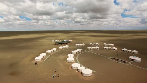 aaerial flying across white nomad tent camp in the middle of huge sandy desert