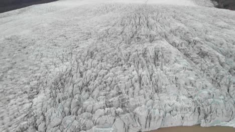 aerial, tilt up, drone shot, overlooking ice masses, at the jokulsarlon glacier, on a foggy, overcast, summer evening, in iceland