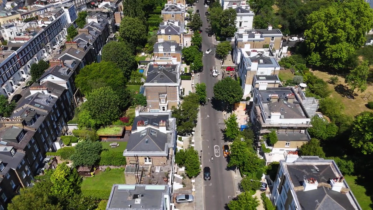 Case d'epoca con giardini sul retro, ampliamenti vetrati e terrazze sul tetto fiancheggiano una strada tranquilla di immobili residenziali di pregio