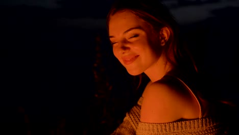 young caucasian ginger tende girl sitting by the fire in the nature, smiling and looking at the camera, portrait