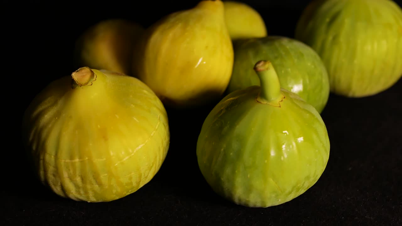 A shot of a few frresh figs spinning on a black surface, with a very short deep of field