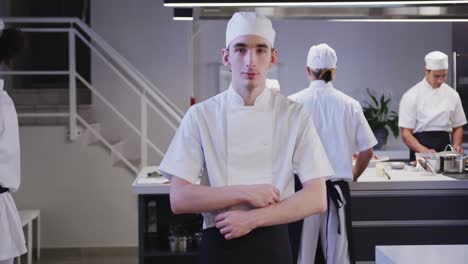 cocinero caucásico que trabaja en la cocina de un restaurante mirando a la cámara y sonriendo