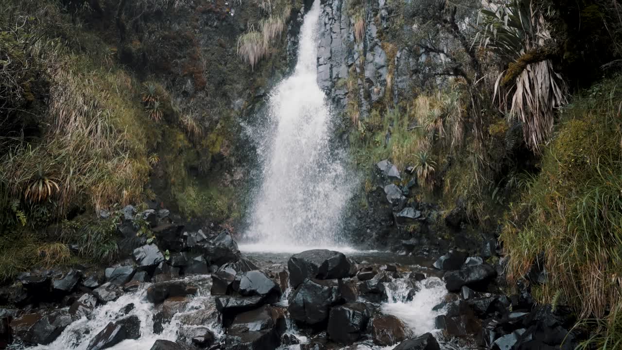 Waterval stroomt krachtig van een torenhoge rotsachtige berg, tijdens een wandeling in het Cayambe Coca Reservaat nabij Papallacta, Ecuador