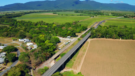 aerial view of road bridge through fields and near mountain landscape in cairns, queensland, australia