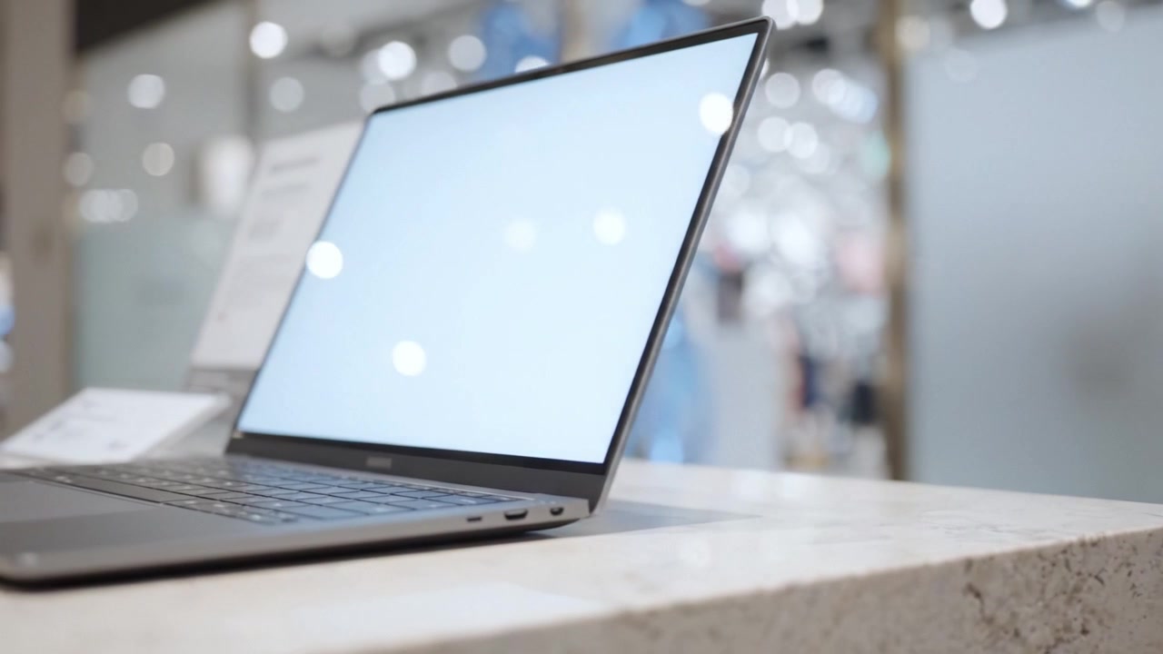 Elegante laptop in esposizione in un moderno ambiente di vendita al dettaglio con illuminazione soffusa e sfondo sfocato che offre un'esperienza tecnologica innovativa.