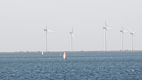 wind surfers on a sunny day with wind turbines in the background