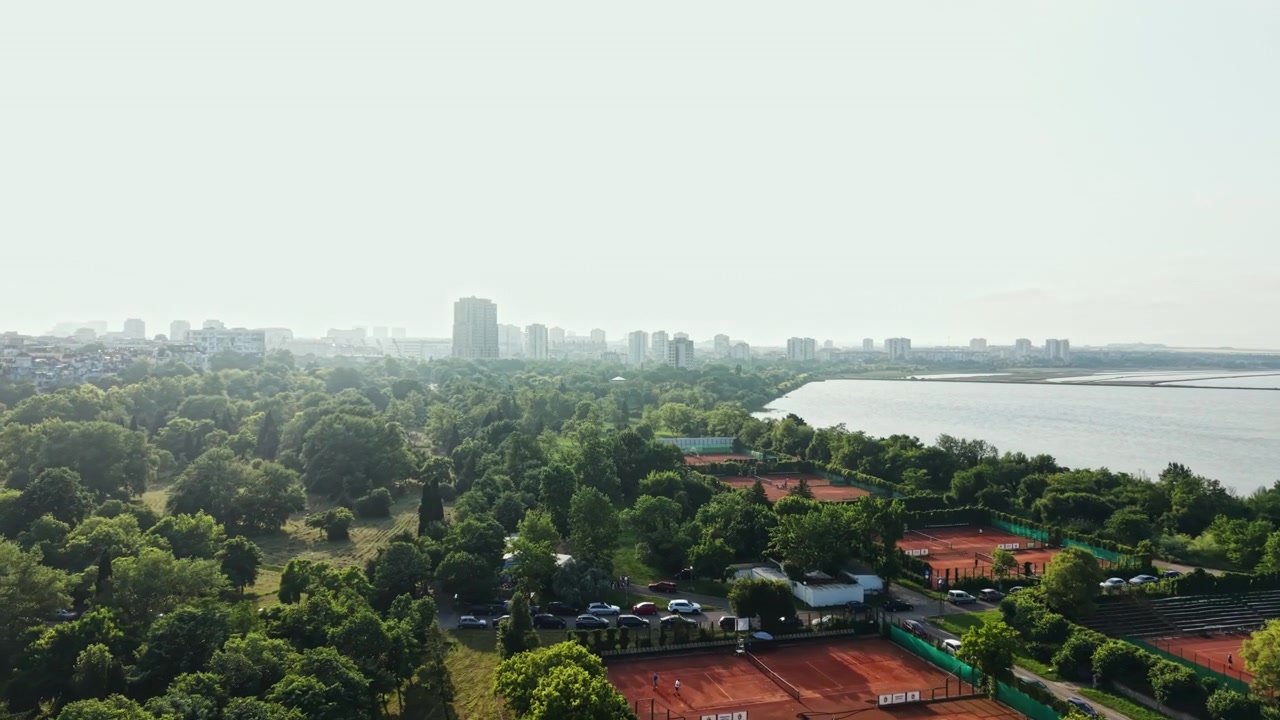 Vista di un parco verde vicino a un fiume con edifici sullo sfondo di giorno in una città.