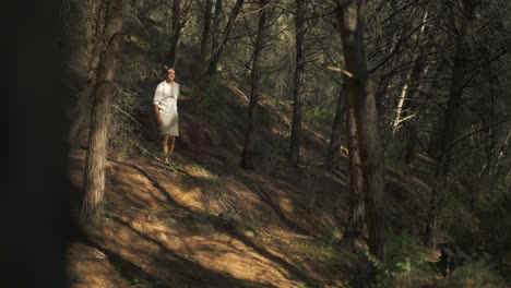 joven hippie amante de la naturaleza caminando descalzo por el bosque usando ropa natural
