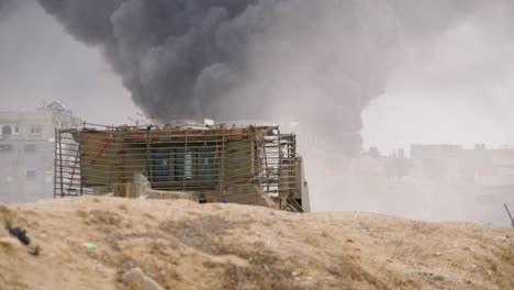 bulldozer blindado idf caterpillar d9 passando por ruas destruídas com edifícios bombardeados e fumaça de fogo maciça em fundo na guerra entre israel e hamas