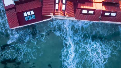 aerial view of ocean waves crashing into oceanfront homes