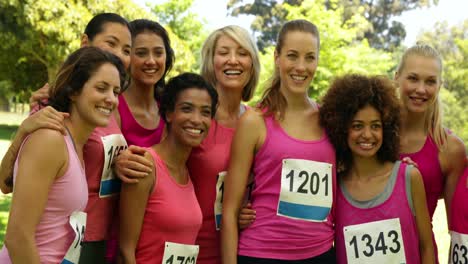 smiling woman racing pink for breast cancer awareness in the park