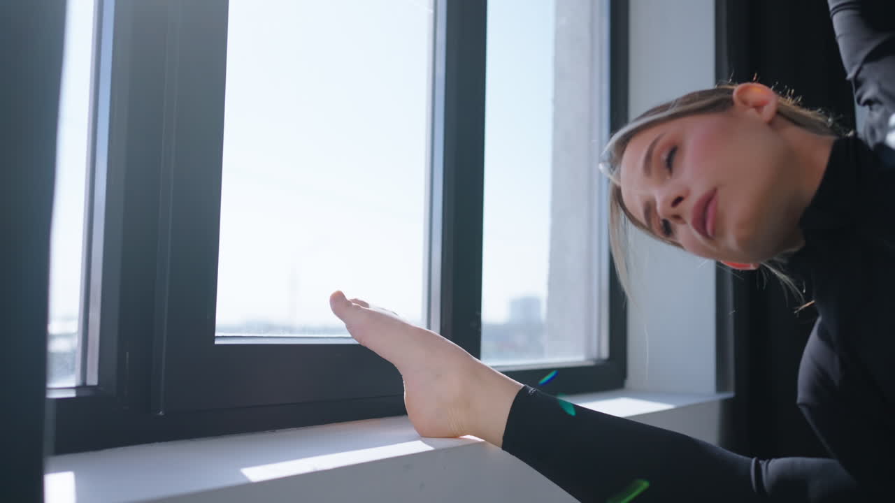 창문 에서 으로 갈라진 요가 자세를 하는 여자