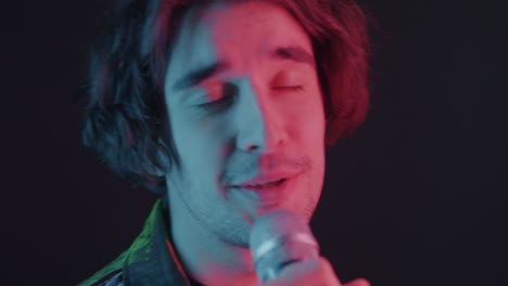 man singing into microphone with colorful lights