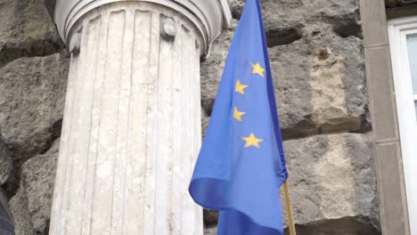 Ondeando-La-Bandera-De-La-Unión-Europea-Frente-A-La-Pared-De-Piedra