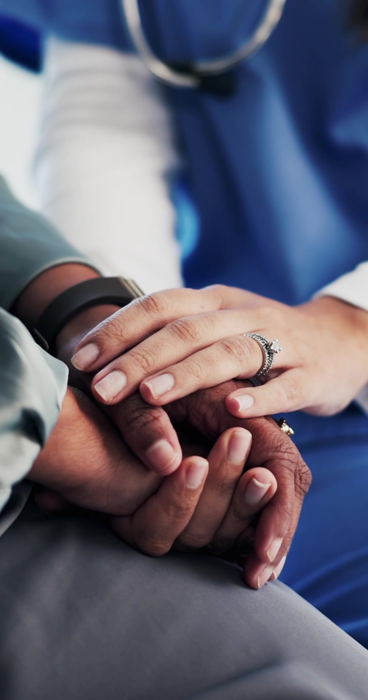 Medico che conforta il paziente tenendogli le mani in un contesto medico