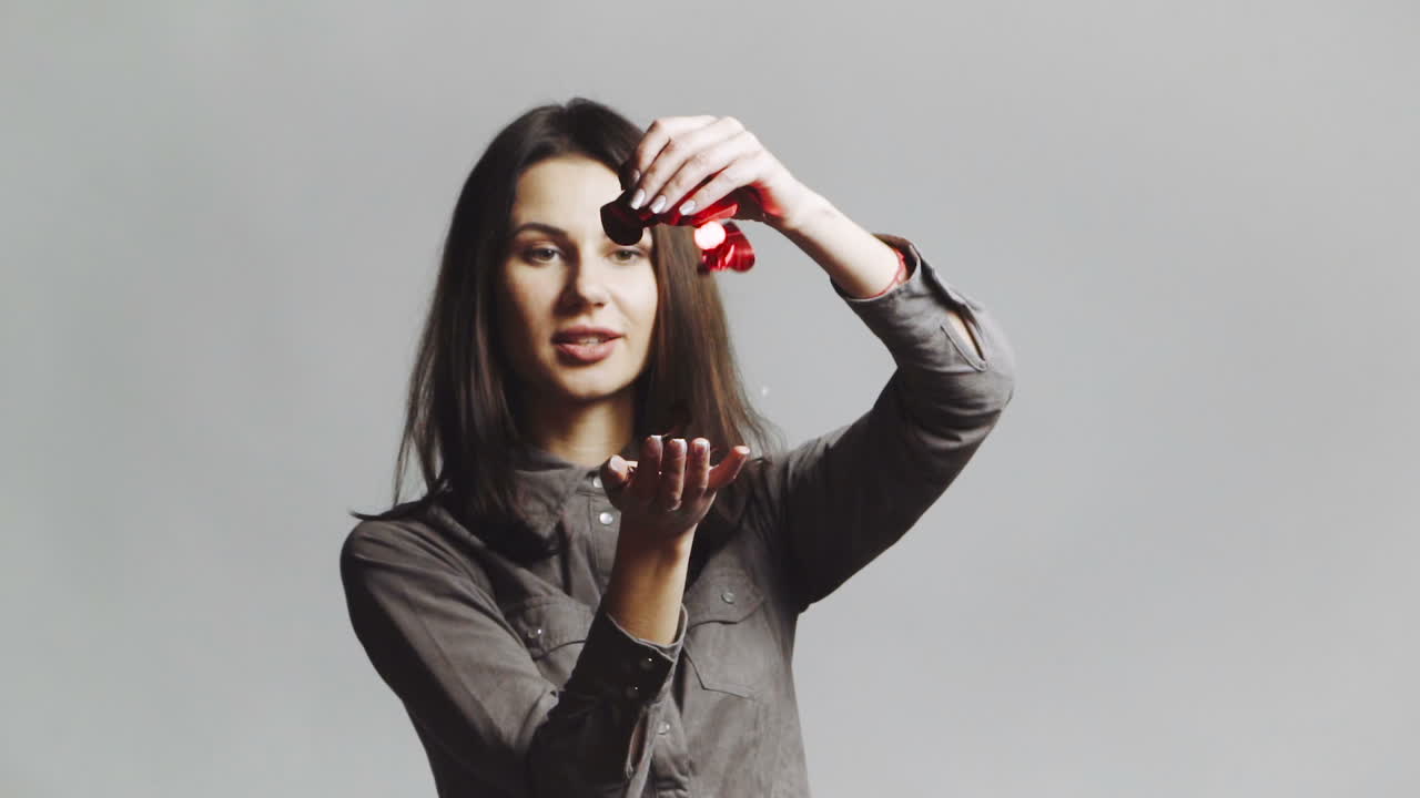 Girl blowing multicolor confetti. Young woman celebrating and blowing confetti decorations