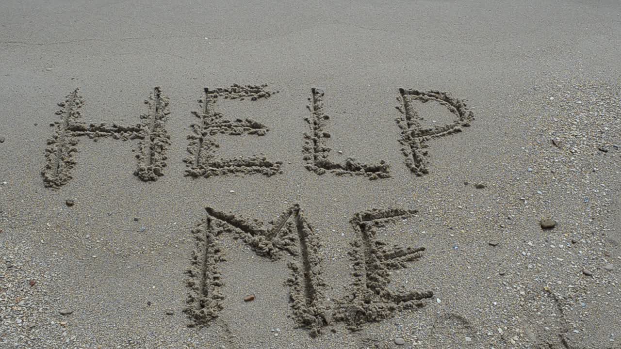 Hjælp-skilt i sandet på en tropisk havstrand. Optagelse på stranden