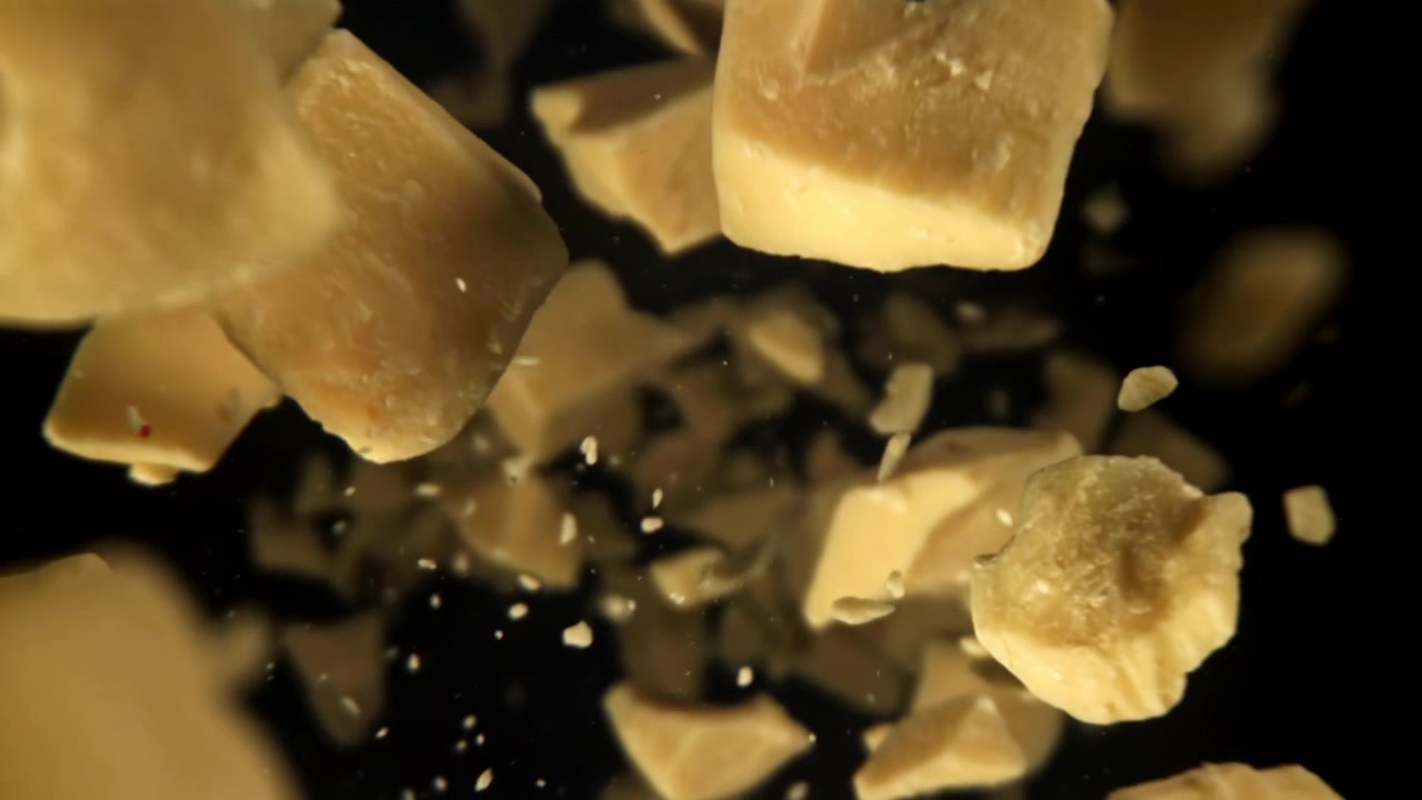 Pezzi di Parmigiano in caduta al rallentatore su sfondo nero
