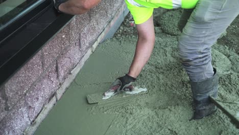 construction worker spreading concrete cement flooring with trowel