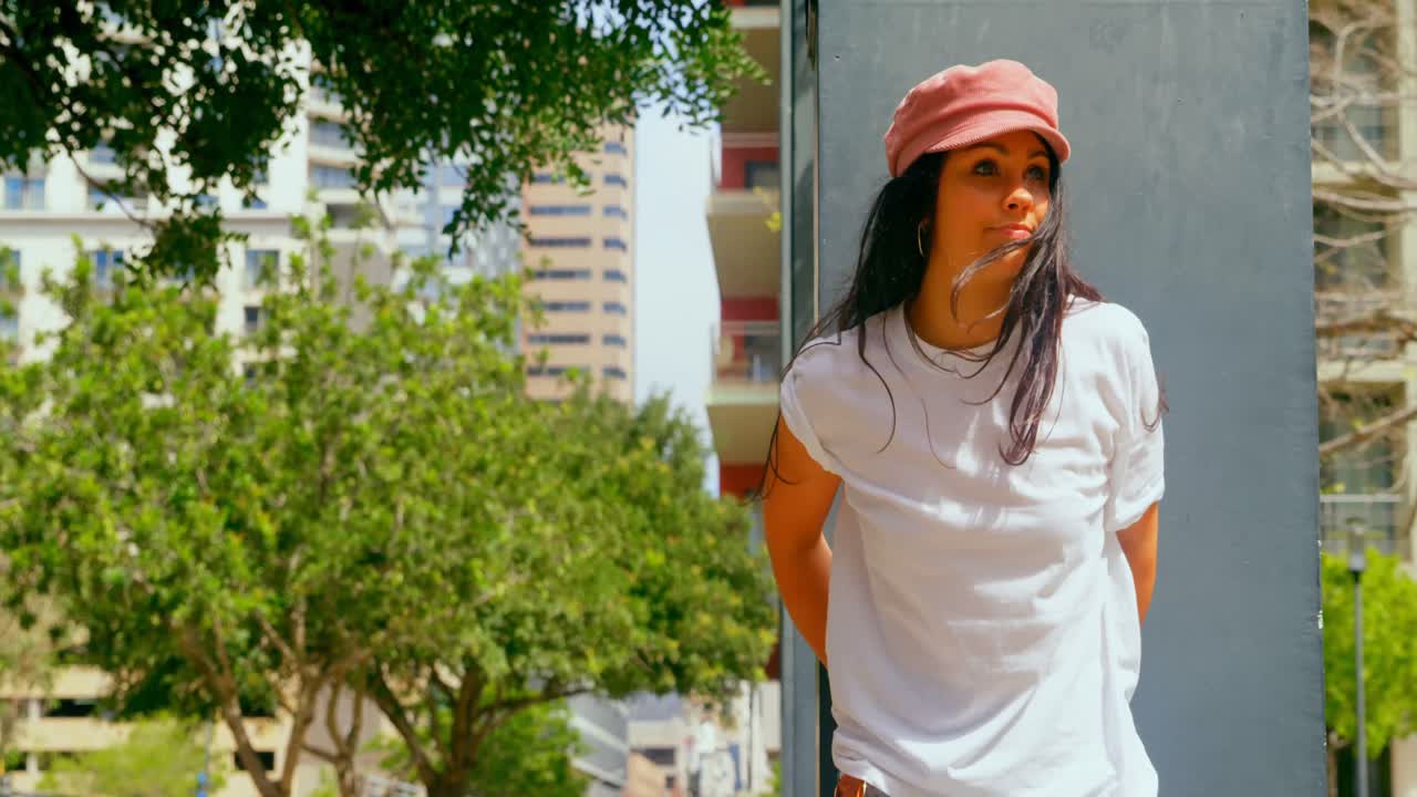 hermosa mujer apoyada en un pilar en la ciudad 4k