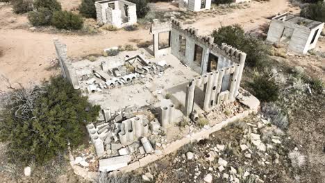 Edificio-Abandonado-Estructura-De-Hormigón-Destruida-Por-El-Cartel-En-El-Alto-Desierto-Del-Sur-De-California-En-Un-Día-Nublado-Con-Una-órbita-Aérea-De-Humor-Apocalíptico-60fps