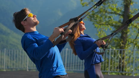 couple working out with suspension trainer outdoors