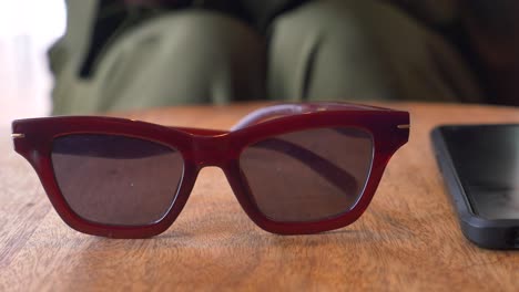 red sunglasses on a wooden table in a cafe