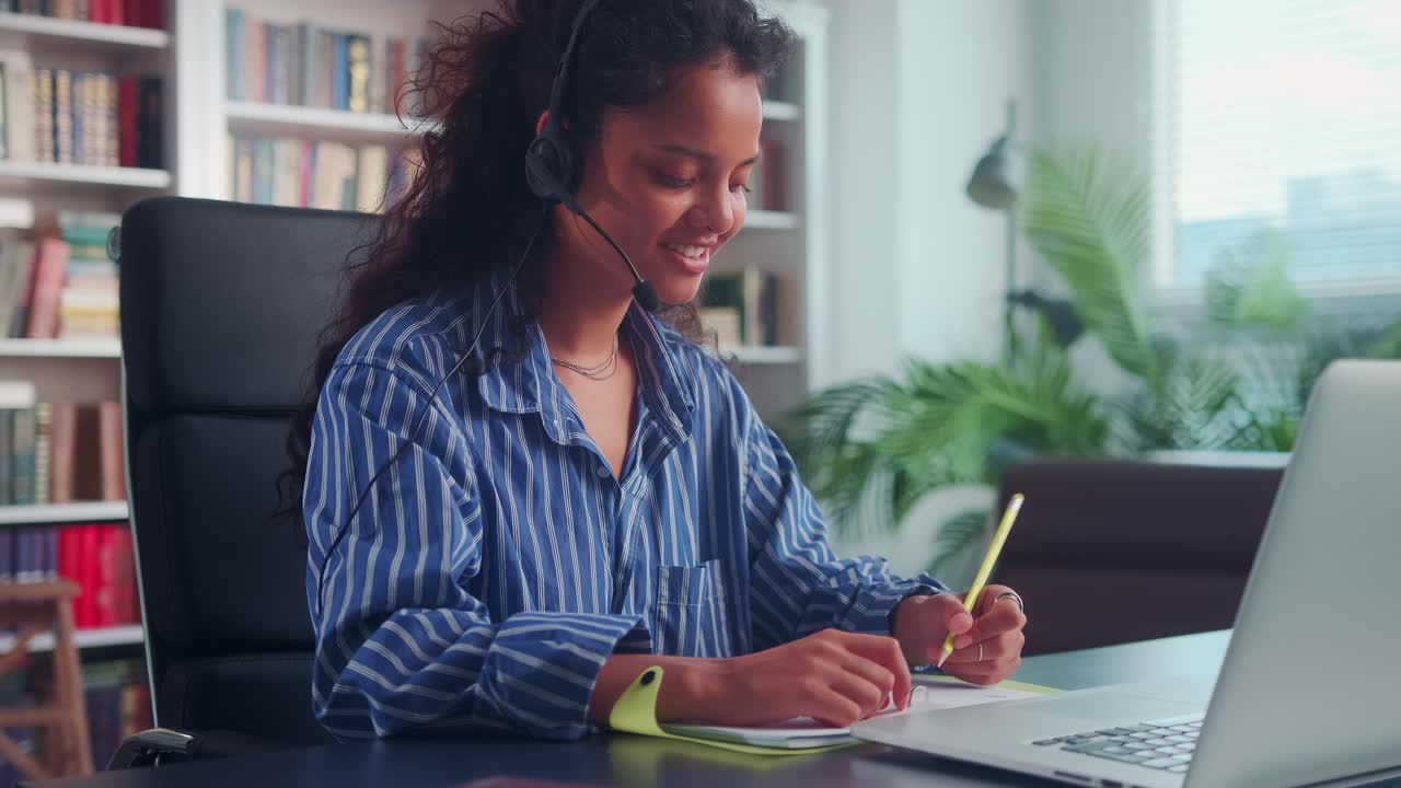 Indian female student in headphones look at laptop screen study online from home