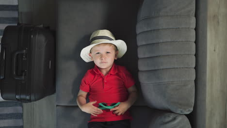 little tourist in hat takes off sunglasses looking in camera