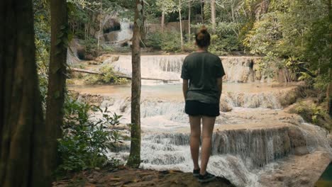 Atractiva-Joven-Caminando-Junto-A-La-Cascada-En-El-Parque-Nacional-De-Erawan,-Tailandia