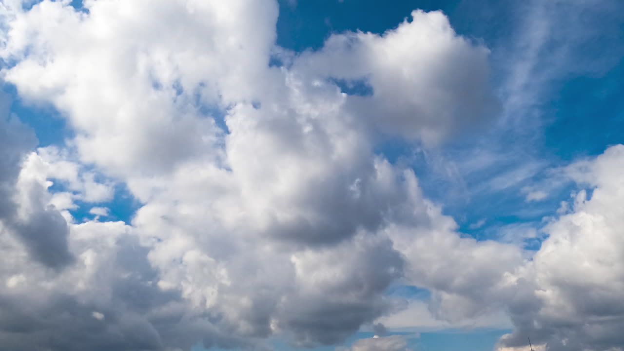 Flying below white soft cumulus clouds. Beautiful blue sky at backdrop. Low angle view. Timelapse.