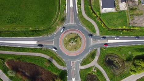 roundabout in the netherlands surrounded by green fields and a few buildings