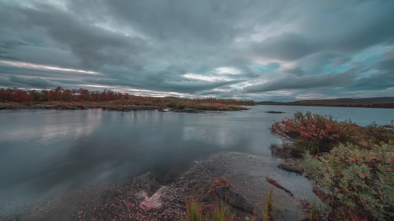una puesta de sol serena sobre un río que se mueve lentamente con nubes que se reflejan en la superficie del agua vidriosa