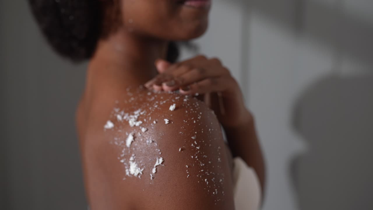 mujer aplicando exfoliante corporal al hombro