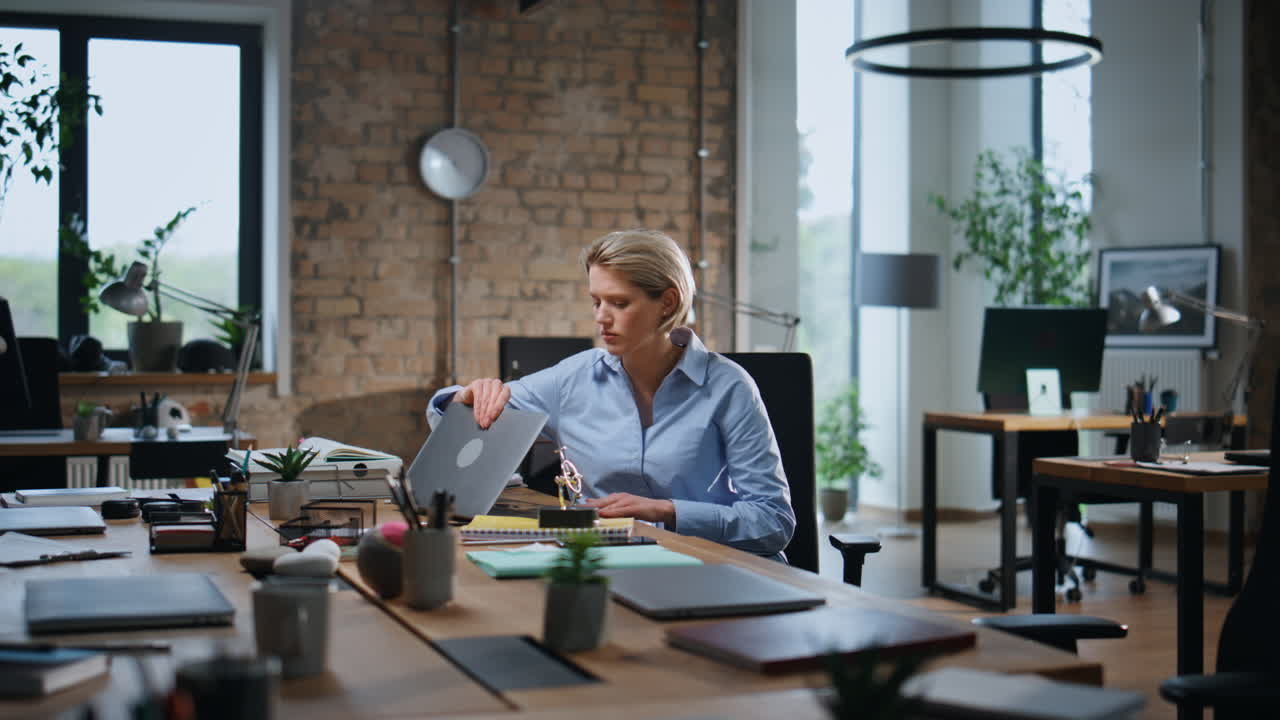 Imprenditrice pensierosa che riflette sul lavoro, seduta in un ufficio moderno vuoto dopo la giornata lavorativa.