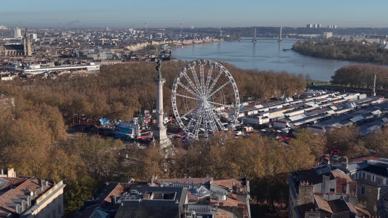 Aerial view of Bordeaux Quinconces, bustling riverside fair with a giant Ferris wheel in a vibrant city landscape