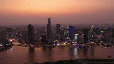 Ho-Chi-Minh-City,-Vietnam-iconic-Skyline-and-Saigon-river-waterfront-aerial-panorama-on-a-busy-evening-featuring-all-key-buildings-illuminated-against-beautiful-colored-sky