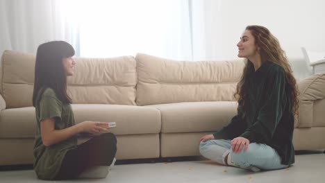 Cute-daughter-and-young-mother-having-fun-at-home---girl-throwing-candies-to-mom's-mouth