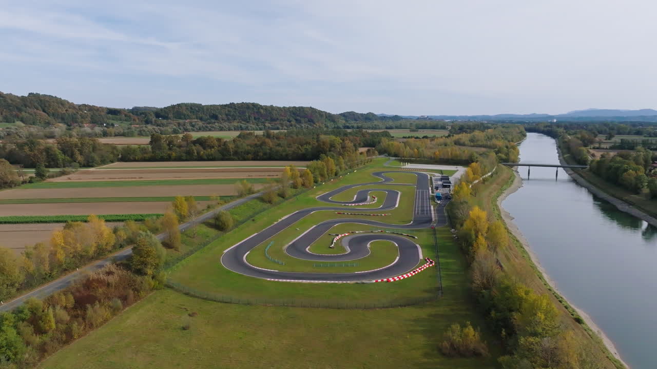 Gokartbane slynger seg gjennom jorder med trær og en elv i nærheten under en klar himmel i dagslys