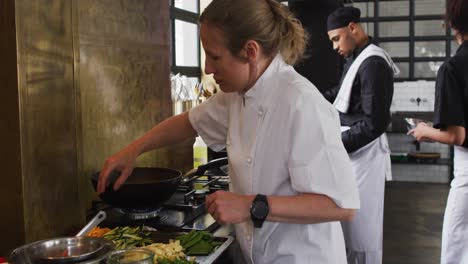 caucasian female chef teaching diverse group preparing dishes and smiling