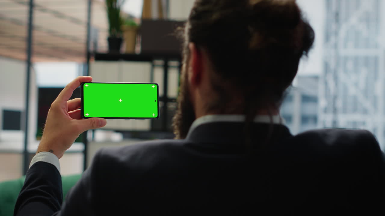 Focused chief executive officer looks at chroma key display on phone