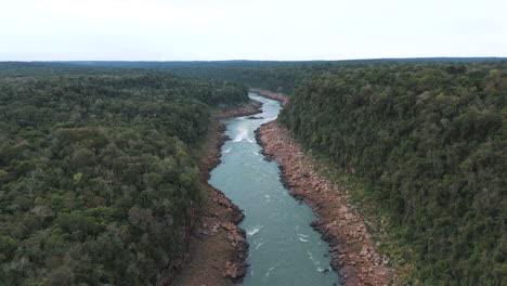 a drone image over the iguaçu river, showing low water flow surrounded by dense jungle on a cloudy day