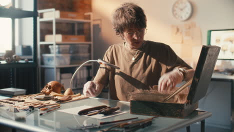 female archaeologist examining historical artifacts at desk in laboratory