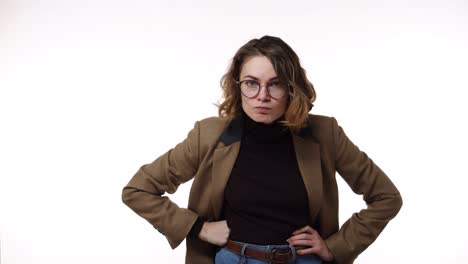 angry, irritated emotions. hush and keep silence. caucasian brunette woman in glasses with finger on lips showing silent or hush gesture isolated on white background. girl wearing black blazer and strict brown jacket