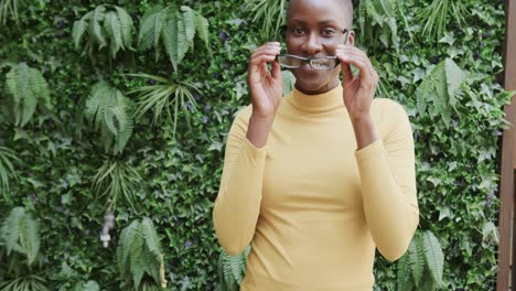 Retrato-De-Una-Empresaria-Afroamericana-Quitándose-Gafas-Y-Sonriendo-En-El-Jardín,-Cámara-Lenta