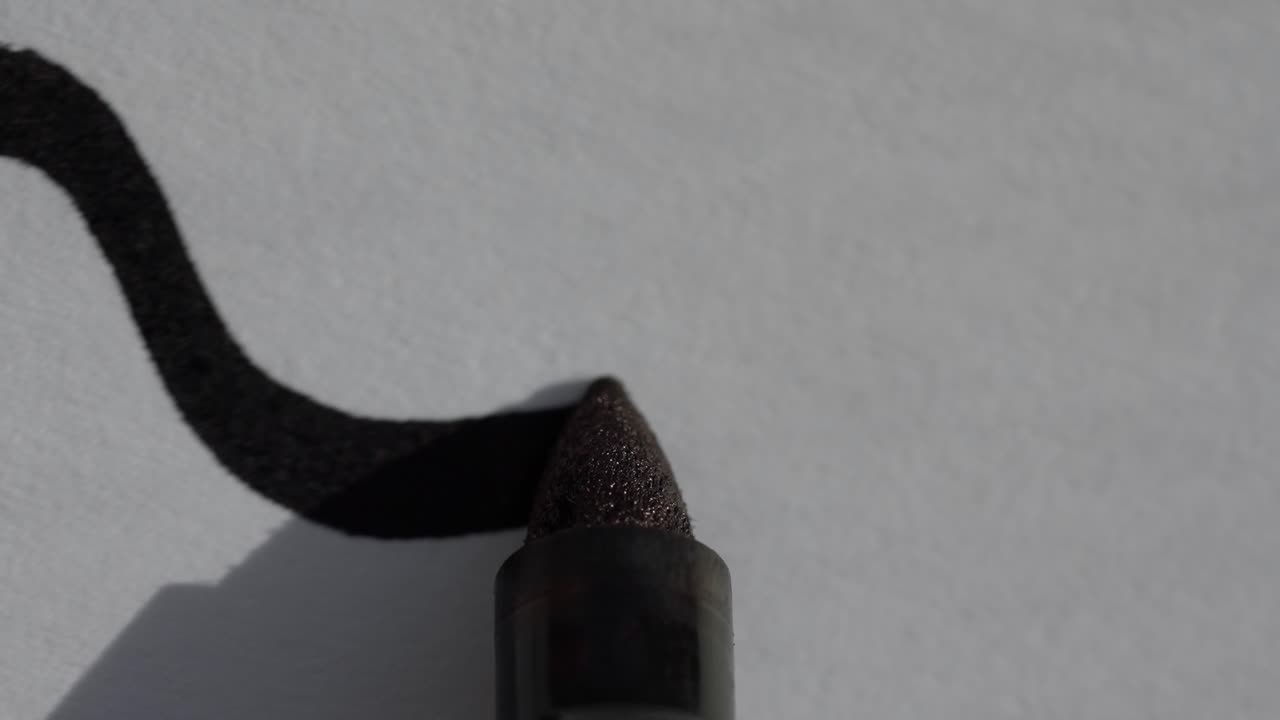 macro close up de un marcador permanente de sharpie negro dibujando una línea curva en un pedazo de papel blanco
